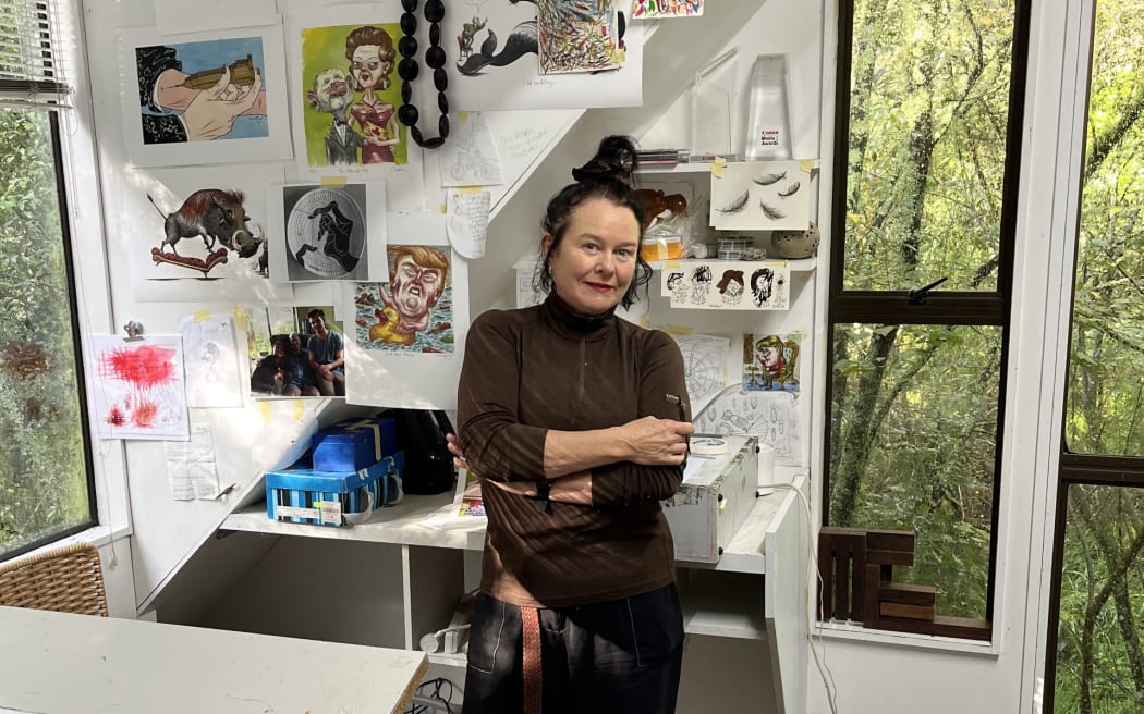 Cartoonist, satirist, and ceramicist Anna Crighton stands in her studio.