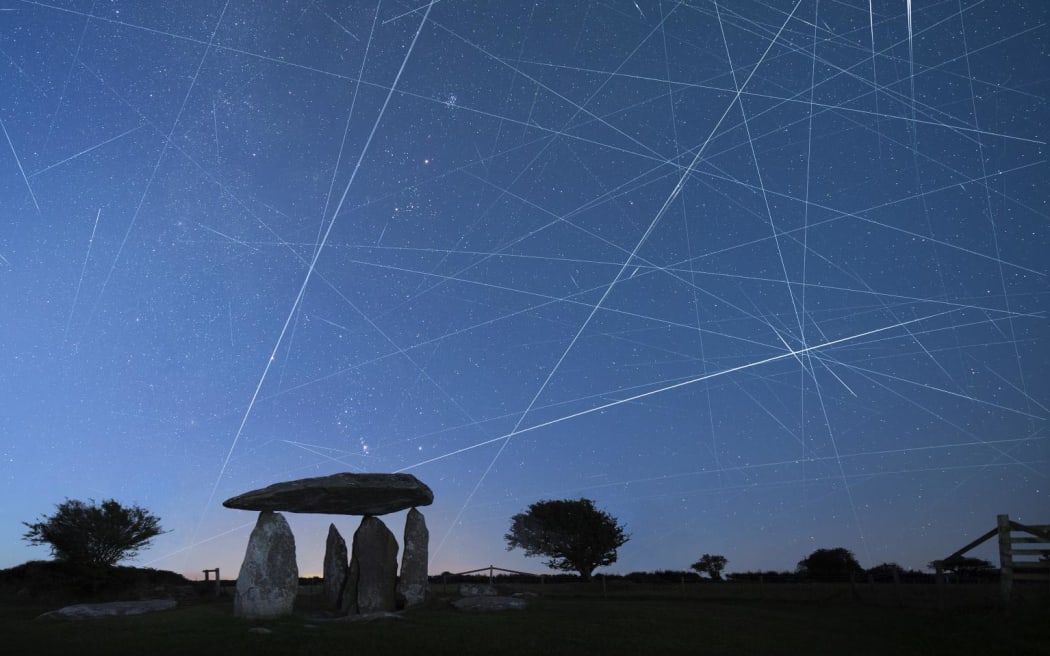 Two hours before dawn the sunlit trails of constellations of Orion, Taurus and the Milky Way are captured individually using long-exposure photography which also captures numerous satellites crossing the sky including the International Space Station, the Starlink mega-constellation and various rocket bodies. The images have then been digitally combined to form one image.