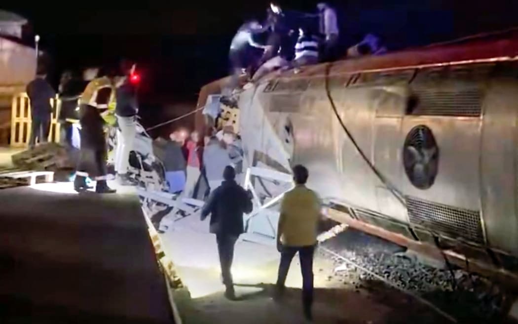 This video grab taken from UGC images posted on social media and verified by AFPTV teams in Madrid, shows emergency personnel working after a train accident in Adamuz, southern Spain, on January 18, 2026. At least 21 people died in a train accident near Adamuz, in the Spanish province of Cordoba (south), when a train derailed and collided with another convoy traveling on the opposite track, the Civil Guard told AFP. A train from the Spanish company Iryo traveling from the Andalusian city of Malaga to Madrid 'derailed' near Adamuz, 'encroaching on the adjacent track' where it collided with another train that 'also derailed,' stated the Railway Infrastructure Administrator (Adif), a public entity under the Ministry of Transport, on X. (Photo by -UGC / @eleanorinthesky (via X) / AFP) / RESTRICTED TO EDITORIAL USE – MANDATORY CREDIT «  AFP PHOTO / @ELEANORINTHESKY (VIA X) » - NO SALES NO MARKETING NO ADVERTISING CAMPAIGNS – DISTRIBUTED AS A SERVICE TO CLIENTS [ NO ARCHIVE ]