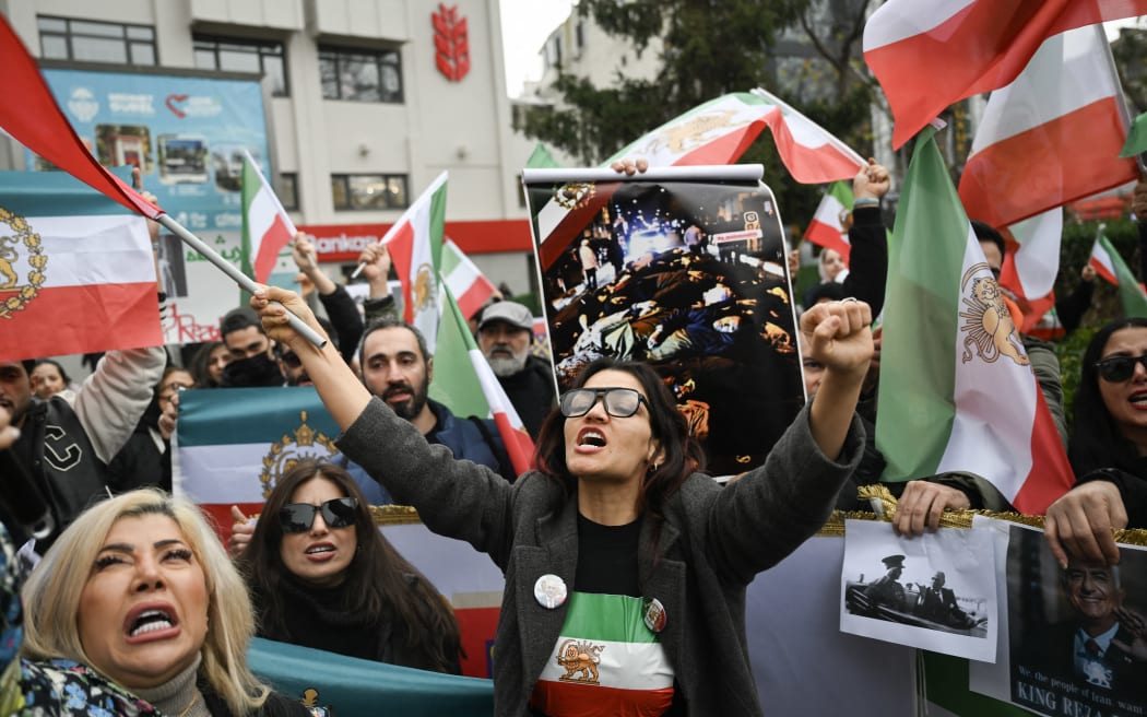 EDITORS NOTE: Graphic content / Anti-Iranian regime protesters hold a flag of Iran from before the 1979 revolution, with the lion ad sun emblems, and an undated image which reportedly shows dead bodies at an undisclosed location, while taking part in a demonstration in solidarity with Iranian protestors and "against the Islamic Repuplic for killing Iranian people" in Yalova, on January 16, 2026. The protest movement in Iran has subsided after a crackdown that has killed thousands under an internet blackout, monitors said on January 16, 2026, one week after the start of the biggest protests in years challenging the Islamic Republic's theocratic system. (Photo by YASIN AKGUL / AFP)