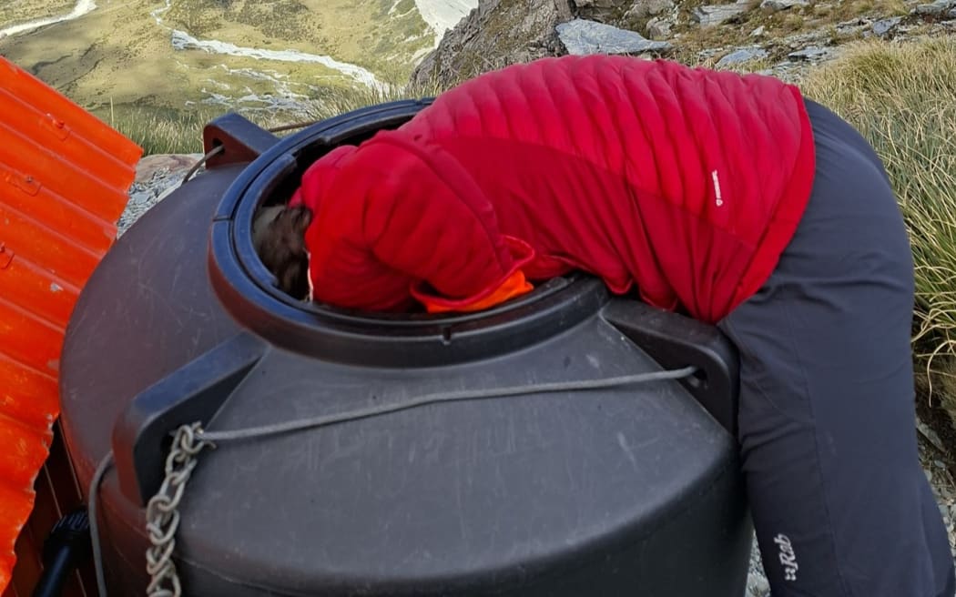 Late last year, a climber staying at the Sefton Bivouac alerted us to a kea trapped in the bivvy’s water tank after hearing calls echoing from it overnight. The lid had been removed, and the inquisitive kea had hopped in but couldn’t get out.
Two members of our DOC Aoraki Mountain Rescue team trekked up to Sefton Bivouac where they found the adult kea perched at the bottom of the tank, seemingly unimpressed by its situation. One team member leaned in and safely lifted the bird out.