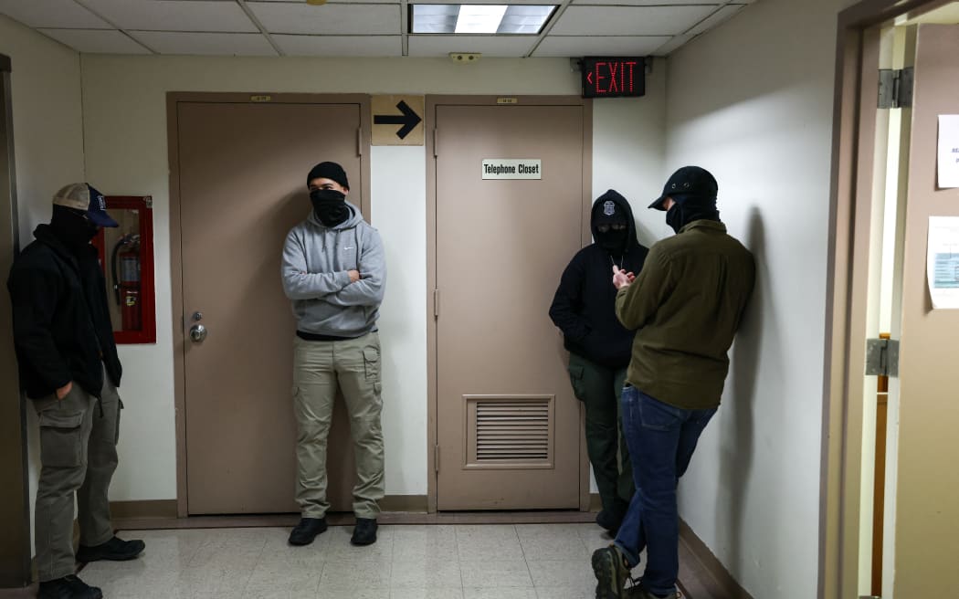 Masked federal agents stand in a hallway at the New York Federal Plaza Immigration Court inside the Jacob K. Javitz Federal Building in New York on December 22, 2025. US President Donald Trump has made deporting undocumented immigrants a key priority for his second term, after successfully campaigning against an alleged