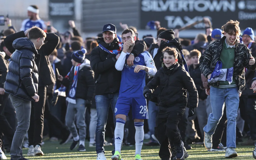 Macclesfield's English midfielder #28 James Edmondson (C) is surrounded by supporters after they storm the pitch to celebrate the team's victory at the end of the English FA Cup third round football match between Macclesfield Town and Crystal Palace at Leasing.com Stadium, Moss Rose in Macclesfield, northern England on January 10, 2026. (Photo by Darren Staples / AFP) / RESTRICTED TO EDITORIAL USE. NO USE WITH UNAUTHORIZED AUDIO, VIDEO, DATA, FIXTURE LISTS, CLUB/LEAGUE LOGOS OR 'LIVE' SERVICES. ONLINE IN-MATCH USE LIMITED TO 120 IMAGES. AN ADDITIONAL 40 IMAGES MAY BE USED IN EXTRA TIME. NO VIDEO EMULATION. SOCIAL MEDIA IN-MATCH USE LIMITED TO 120 IMAGES. AN ADDITIONAL 40 IMAGES MAY BE USED IN EXTRA TIME. NO USE IN BETTING PUBLICATIONS, GAMES OR SINGLE CLUB/LEAGUE/PLAYER PUBLICATIONS. /