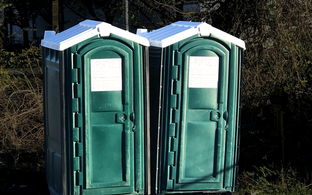 Two green portable toilets outdoors.