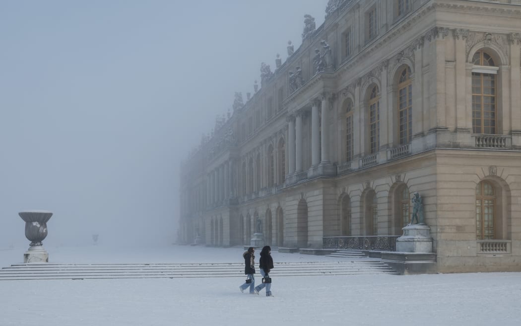 Pedestrians walk through the snow-blanketed gardens of Versailles outside Paris on January 6, 2026. Some of the winter's coldest weather so far hit travel in Britain, France and the Netherlands on January 5, closing roads, grounding flights and forcing train cancellations, including on Eurostar, just days after a power outage caused major disruption. (Photo by GEOFFROY VAN DER HASSELT / AFP)