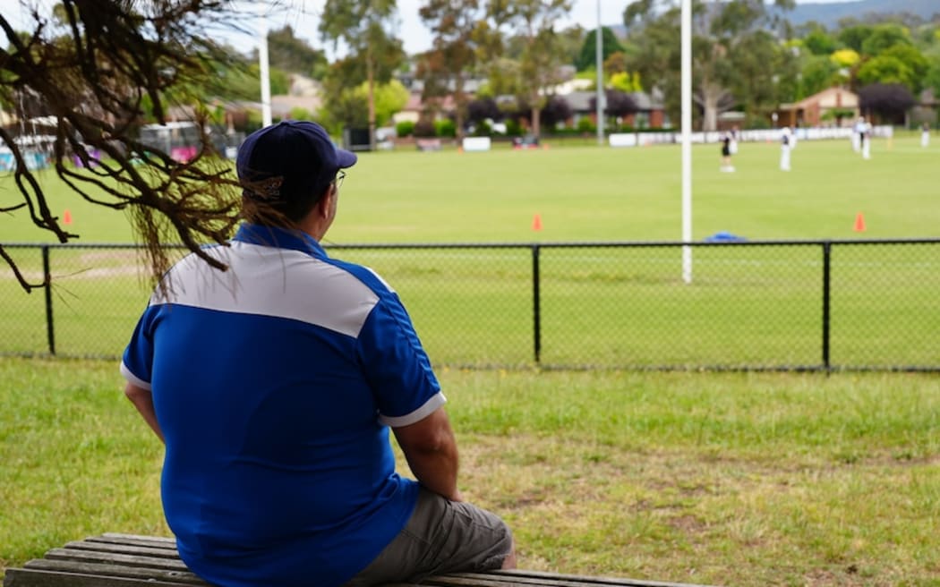 Jace Austin watches a cricket match where his youngest son is playing.