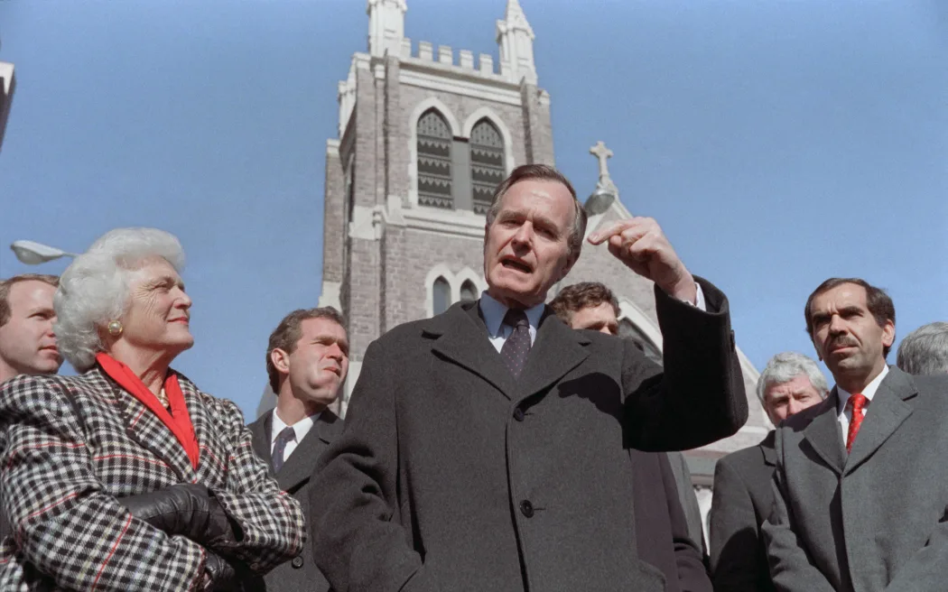 Vice President of the United States George H. W. Bush (C) speaks to the press on his rivalry with senator Robert Dole for the 1988 Republican Presidential nomination, on February 7, 1988 after leaving the mass with his wife Barbara Bush (L) and son George W. Bush (L, behind), on August 18, 1989 at Des Moines, Iowa. (Photo by Mike SPRAGUE / AFP)