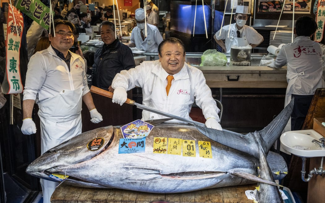 Kiyoshi Kimura (C), president of Kiyomura Corp., the Tokyo-based operator of sushi restaurant chain Sushizanmai, displays a 243-kilogram bluefin tuna at his main restaurant in Tokyo on January 5, 2026, after the New Year's auction at Toyosu fish market. A Japanese sushi entrepreneur paid a record $3.2 million for a giant bluefin tuna January 5 at an annual prestigious new year auction in Tokyo's main fish market, smashing the previous all-time high. (Photo by Yuichi YAMAZAKI / AFP)