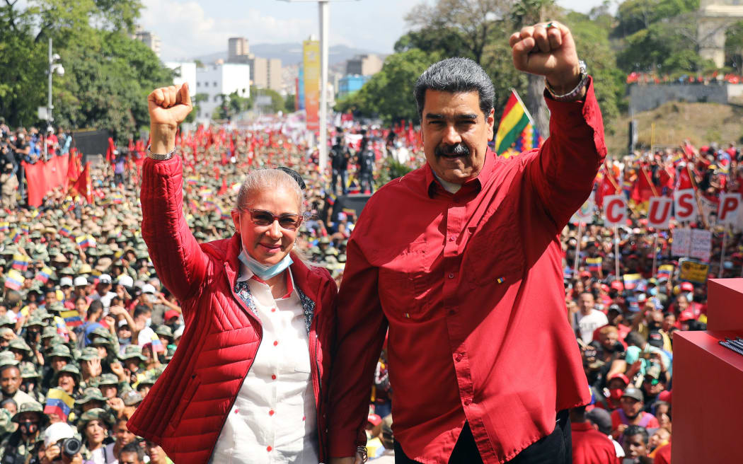 (FILES) Handout photo released by the Miraflores presidential palace press office showing Venezuela's President Nicolas Maduro (R) accompanied by his wife Cilia Flores raising their clenched fists during a civil-military parade to commemorate the 20th anniversary of the coup that briefly removed late Venezuelan president (1999-2013) Hugo Chavez from power, in Caracas on April 13, 2022. President Donald Trump said on January 3, 2026, that US forces had captured Venezuelan leader Nicolas Maduro after launching a "large scale strike" on the South American country. "The United States of America has successfully carried out a large scale strike against Venezuela and its leader, President Nicolas Maduro, who has been, along with his wife, captured and flown out of the Country," Trump said on Truth Social. (Photo by Venezuelan Presidency / AFP) / RESTRICTED TO EDITORIAL USE-MANDATORY CREDIT - AFP PHOTO / VENEZUELAN PRESIDENCY - NO MAFRKETING - NO ADVERTISING CAMPAIGNS - DISTRIBUTED AS A SERVICE TO CLIENTS