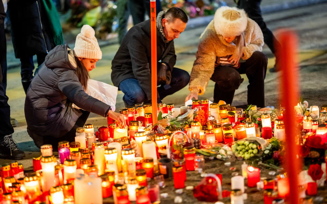 Mourners light candles at a makeshift memorial near the site of a fire that ripped through a bar during New Year's Eve celebrations in the Alpine ski resort town of Crans-Montana killing around 40 people and injuring more than 100 others, in Crans-Montana on January 2, 2026.