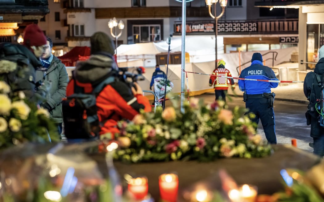 Police control access to the street where a fire ripped through a crowded bar during New Year's Eve celebrations in the Alpine ski resort town of Crans-Montana on January 1, 2026. Several dozen people are presumed dead and around 100 injured after a fire ripped through a crowded bar in the luxury Swiss ski resort of Crans-Montana, Swiss police said on January 1, 2026. Police, firefighters and rescuers rushed to the popular resort, which is set to host the Ski World Cup from January 30, after the fire broke out in the early hours of New Year's Day. (Photo by MAXIME SCHMID / AFP)