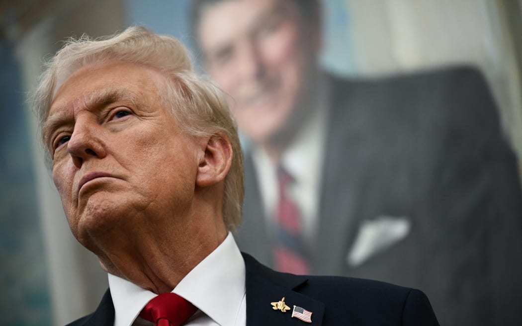A portrait of former US President Ronald Reagan hangs behind US President Donald Trump as Trump makes an announcement in the Oval Office of the White House in Washington, DC, on 30 September, 2025.