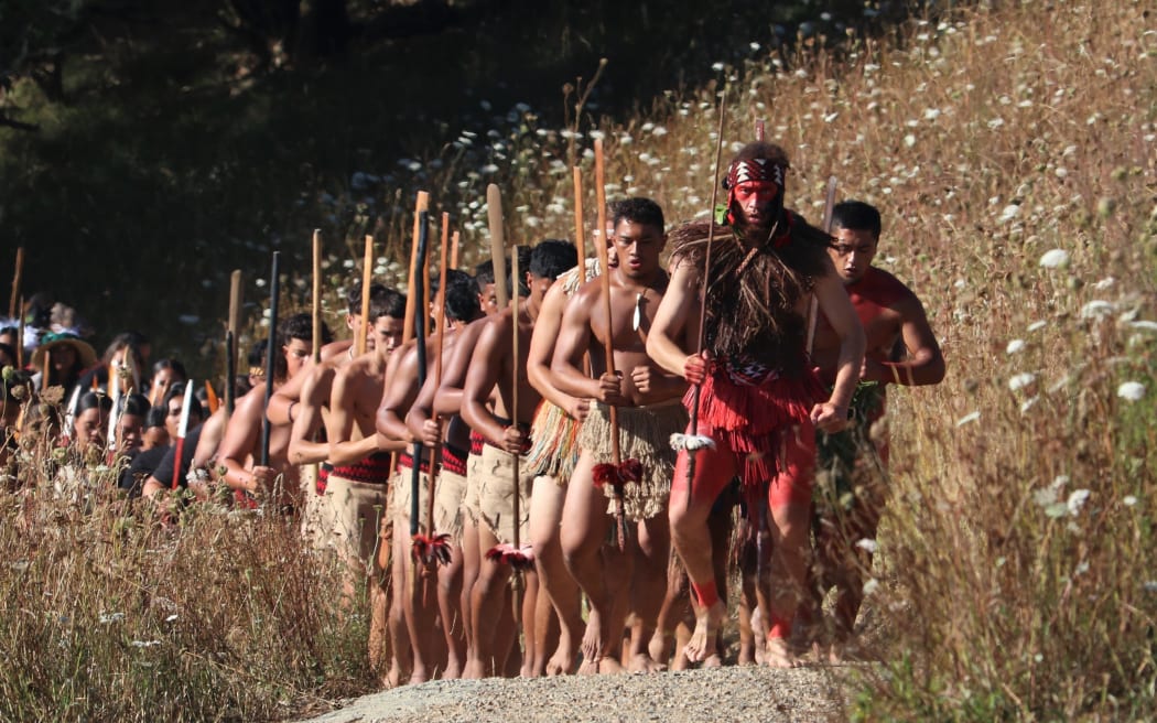 Warriors of mass haka group Te Tira Taua advance on the site of the British encampment during the 2021 commemorations.