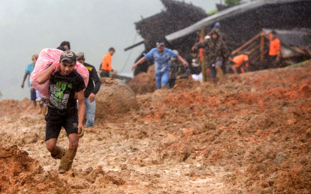Residents evacuate their homes as rescue workers search for survivors at the site of a landslide triggered by heavy rain in Sukabumi, West Java province on January 1, 2019.