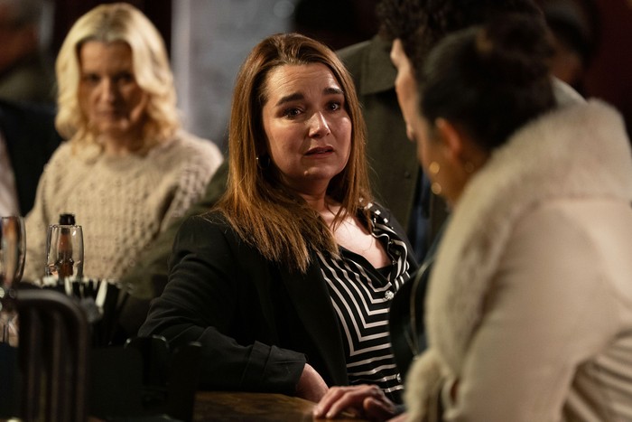 Vicki stands shellshocked in the pub surrounded by Priya, Mark and Kathy in a scene from EastEnders