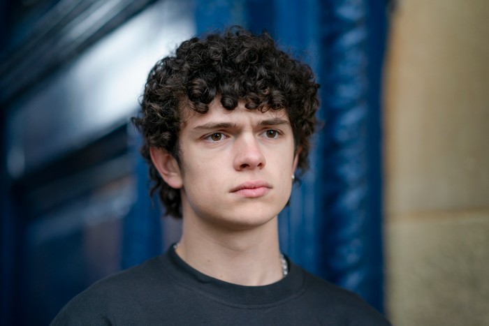 Noah Jupe stars in The Night Manager season 2; in this scene, his character is looking straight ahead and appearing to be troubled by something