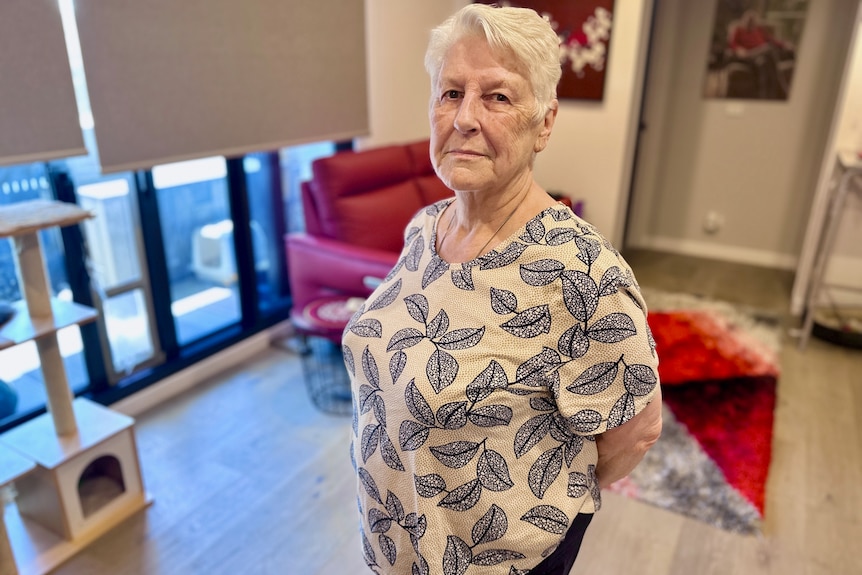 Marie stands seriously in her living room.