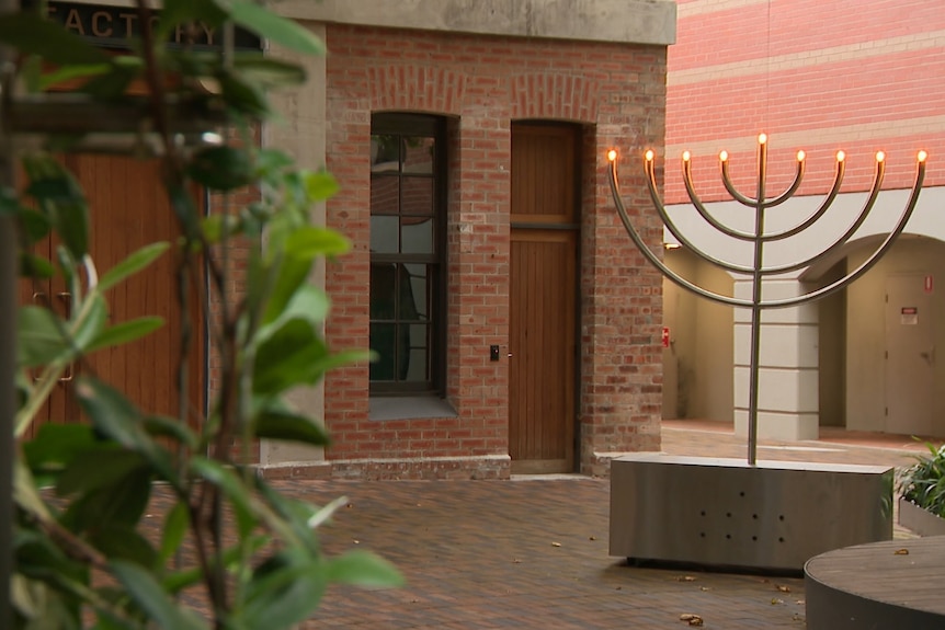 A menorah with electric lights to signify candles stands outside an old brick building where the meeting was being held.