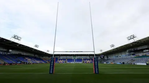 PA Media The inside of the Halliwell Jones Stadium, with pitch and goalposts and tiered seating in view.