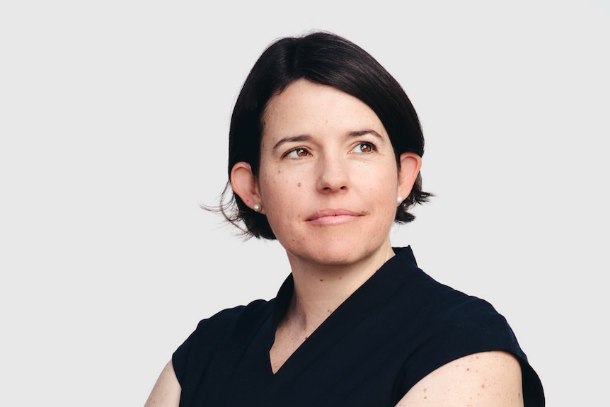 a woman likely in her 40s with short brown hair and a black shirt looking off to the right