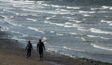 Strong winds whip up waves as a woman and man walk along the beach at English Bay in Vancouver, on Sunday May 5, 2019. THE CANADIAN PRESS/Darryl Dyck