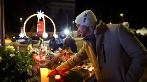 Reuters A man leaves a candle outside the "Le Constellation" bar 