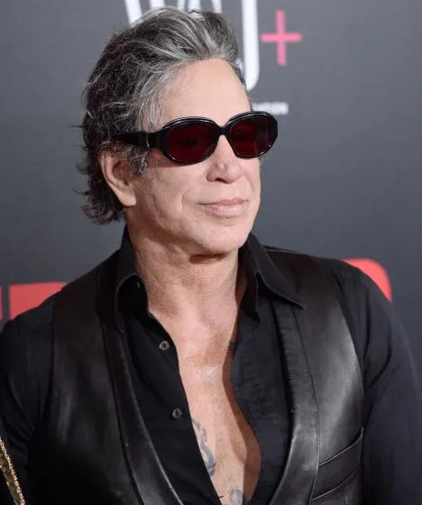 Mickey Rourke looking to one side in dark glasses, a black shirt and black leather vest