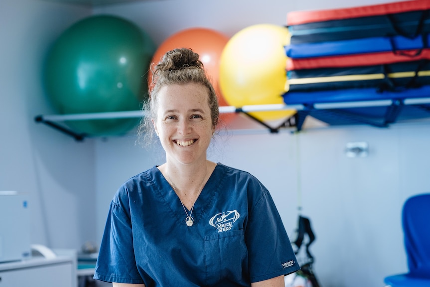 a woman in scrubs smiles at the camera