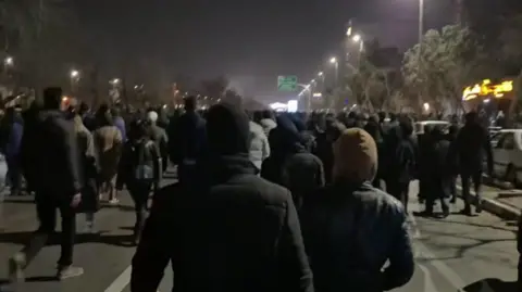 X Protesters walk down a major road in Mashhad, north-eastern Iran, on 8 January 2026