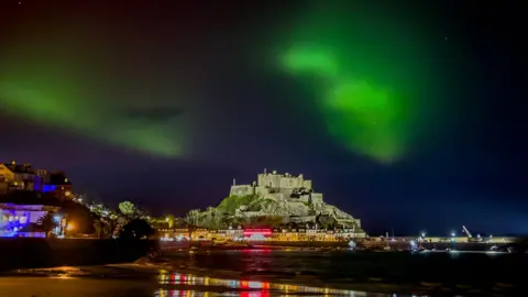 JASON MASTERMAN Green northern lights on top of a castle with a beach in the background 