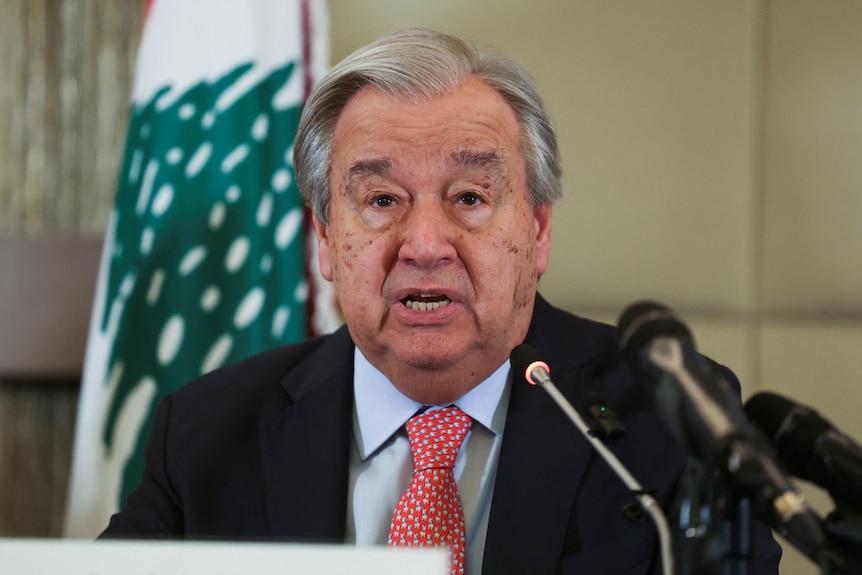 Antonio Guterres sitting in front of a microphone.
