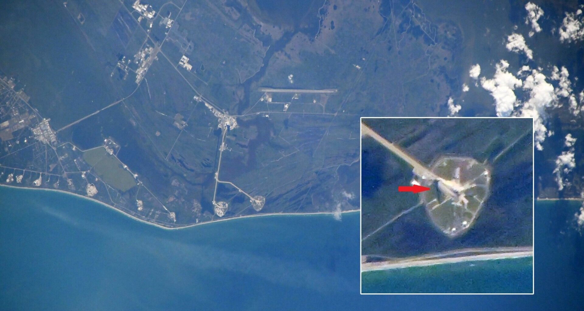 A view of the Florida coastline from space, with the dark green land outlined by a thin white strip of beach before a blue ocean. An inset to the right in a white box shows a red arrow pointing to a white space amidst a green circled off area.