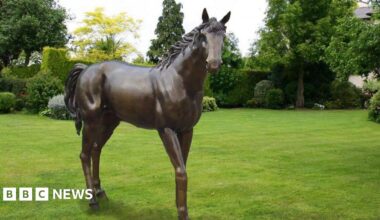 A bronze statue of a horse in a field