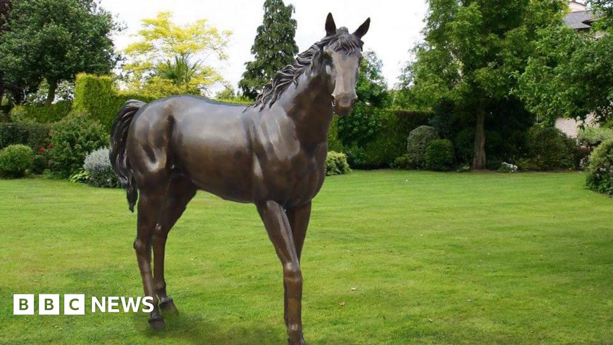 A bronze statue of a horse in a field