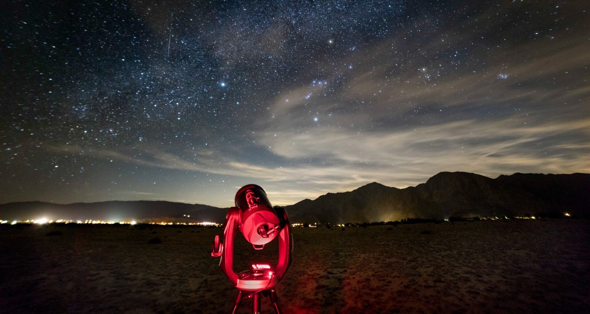 a telescope points upward at a starry night sky