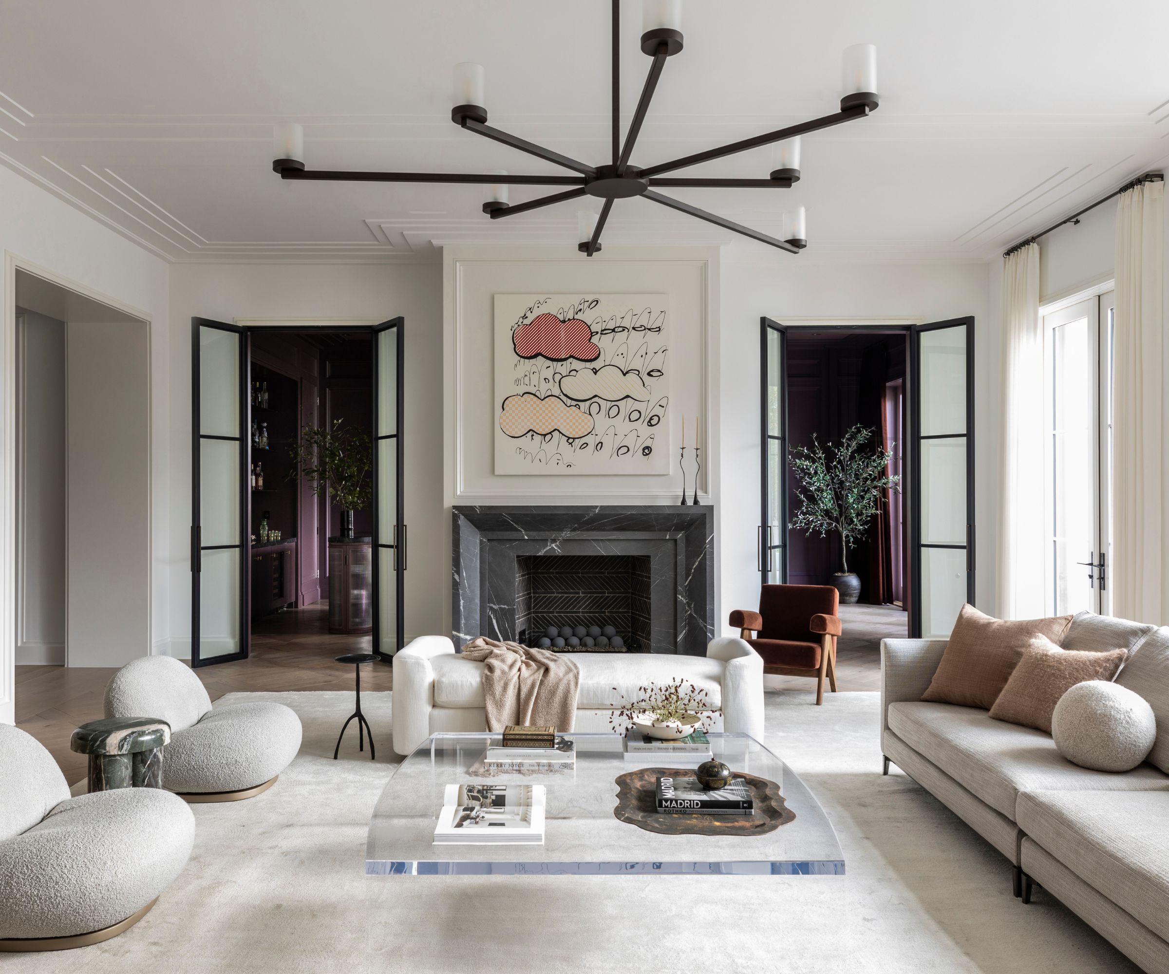 A neutral living room with white walls, cream sofas, and a black marble fireplace