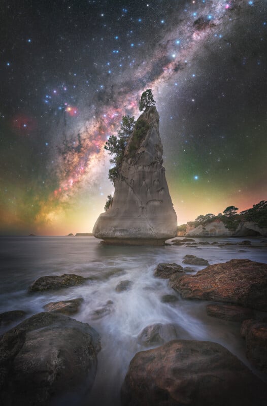 A rock formation in the water with a starry sky.