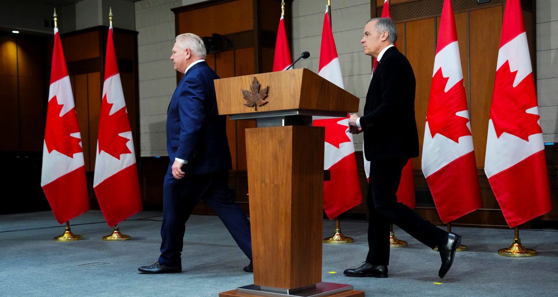 Ontario Premier Doug Ford leads Prime Minister Mark Carney off stage to the right leave following an announcement on Parliament Hill in Ottawa.