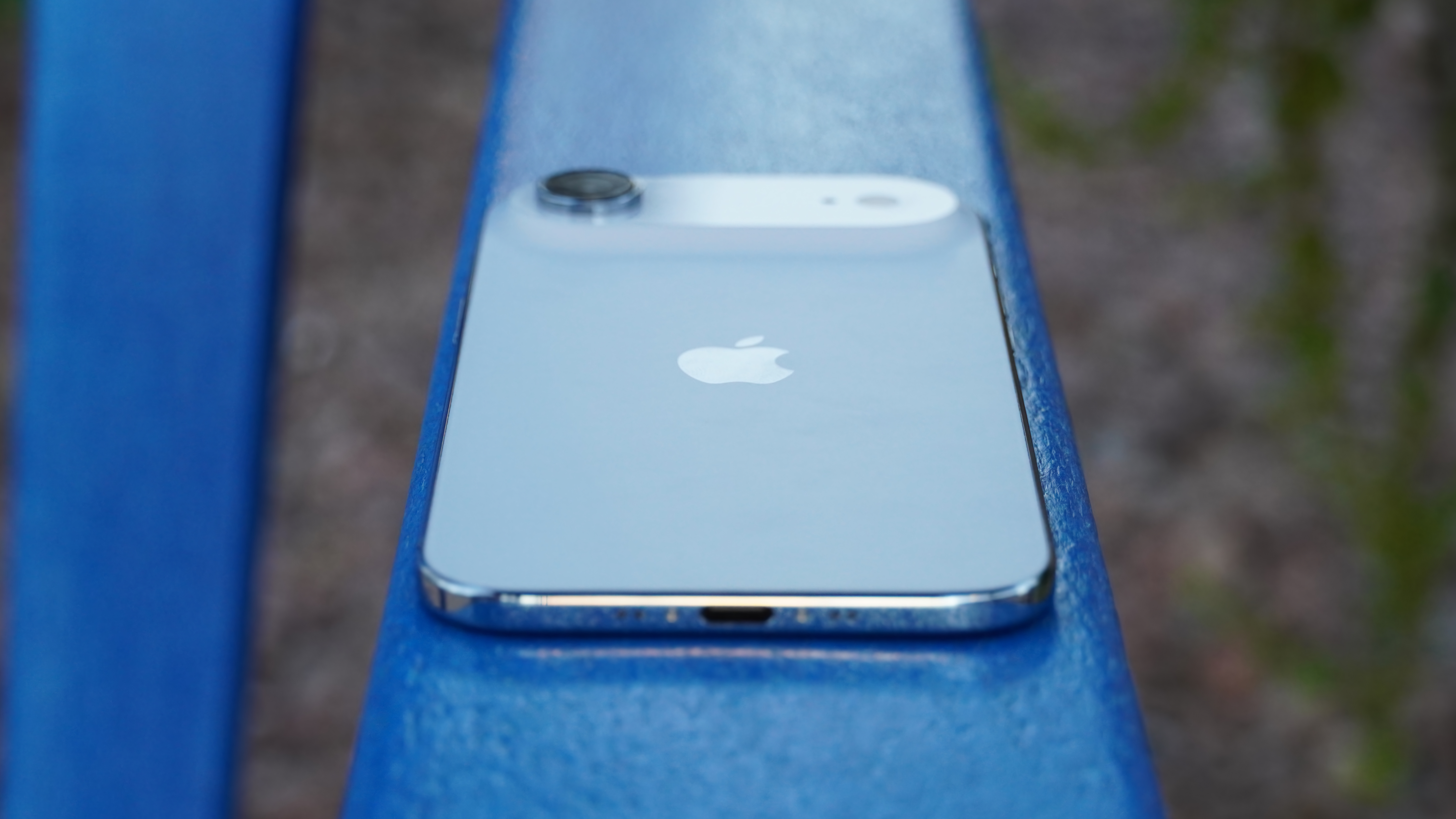 The back of an iPhone Air and USB-C port in Sky Blue on a blue chair.