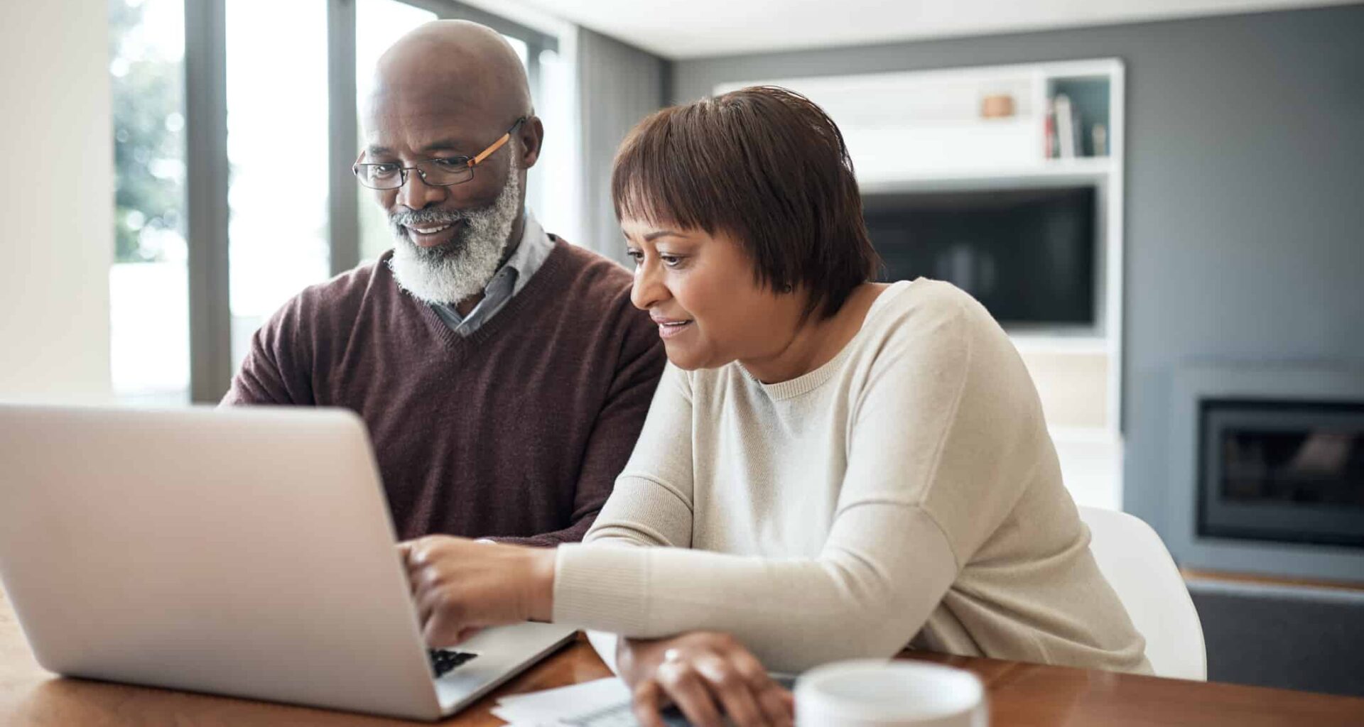 happy senior couple using a laptop in their living room to look at their financial budgets