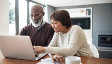happy senior couple using a laptop in their living room to look at their financial budgets
