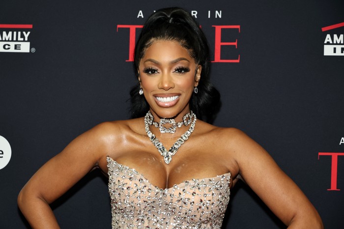 Porsha Williams smiling ahead wearing a bedazzled sleeveless gown and statement jewel necklace.