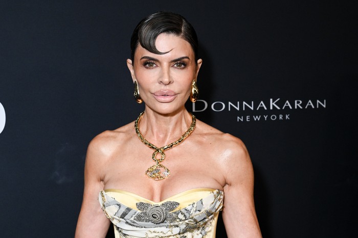 Lisa Rinna looking ahead wearing a sleeveless gown and statement gold necklace.