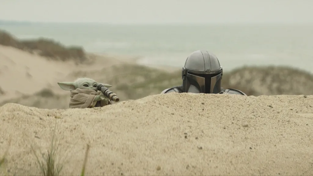 Grogu and Din Djarin spying over hill in Mandalorian and Grogu