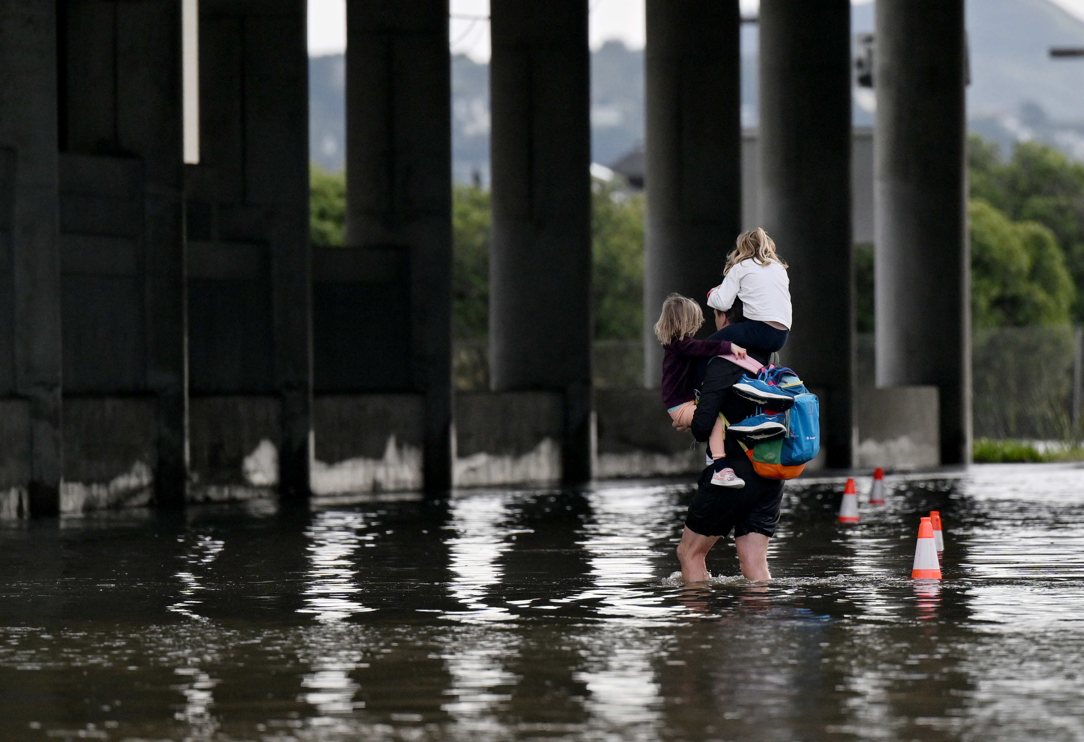 A man carries children through a flooded underpass near the...