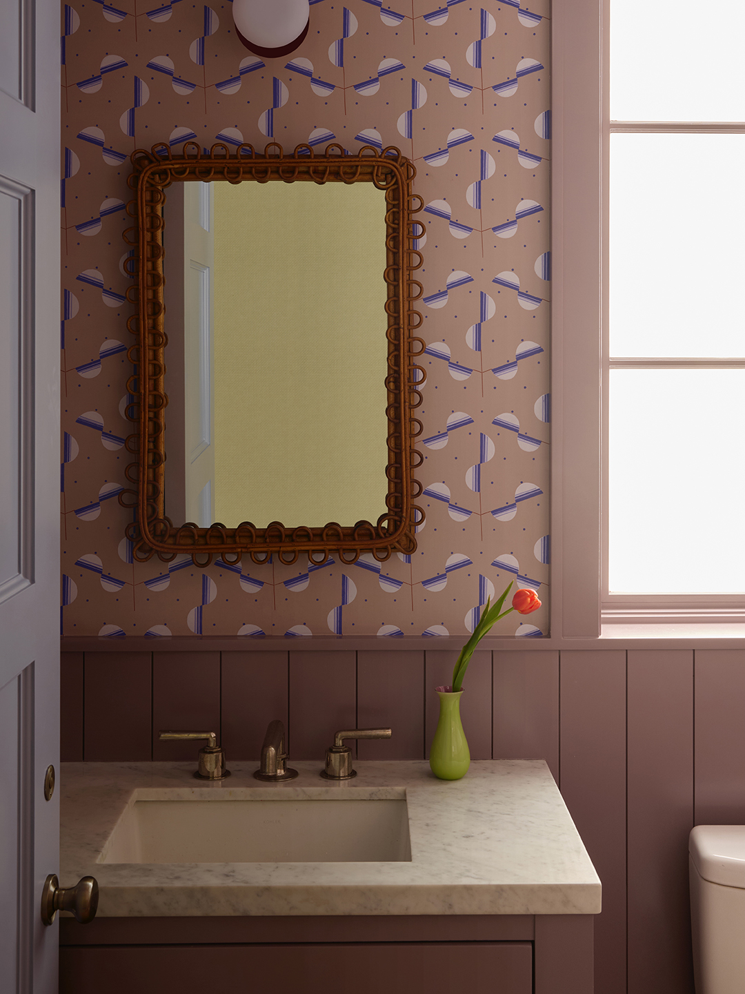 bathroom sink with pink wallpaper and red mirror