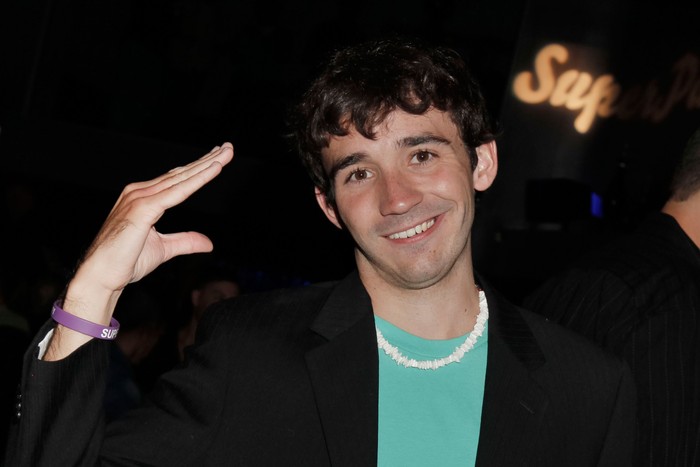 Ian Terry smiling ahead with one hand raised making the shape of a duck's bill.