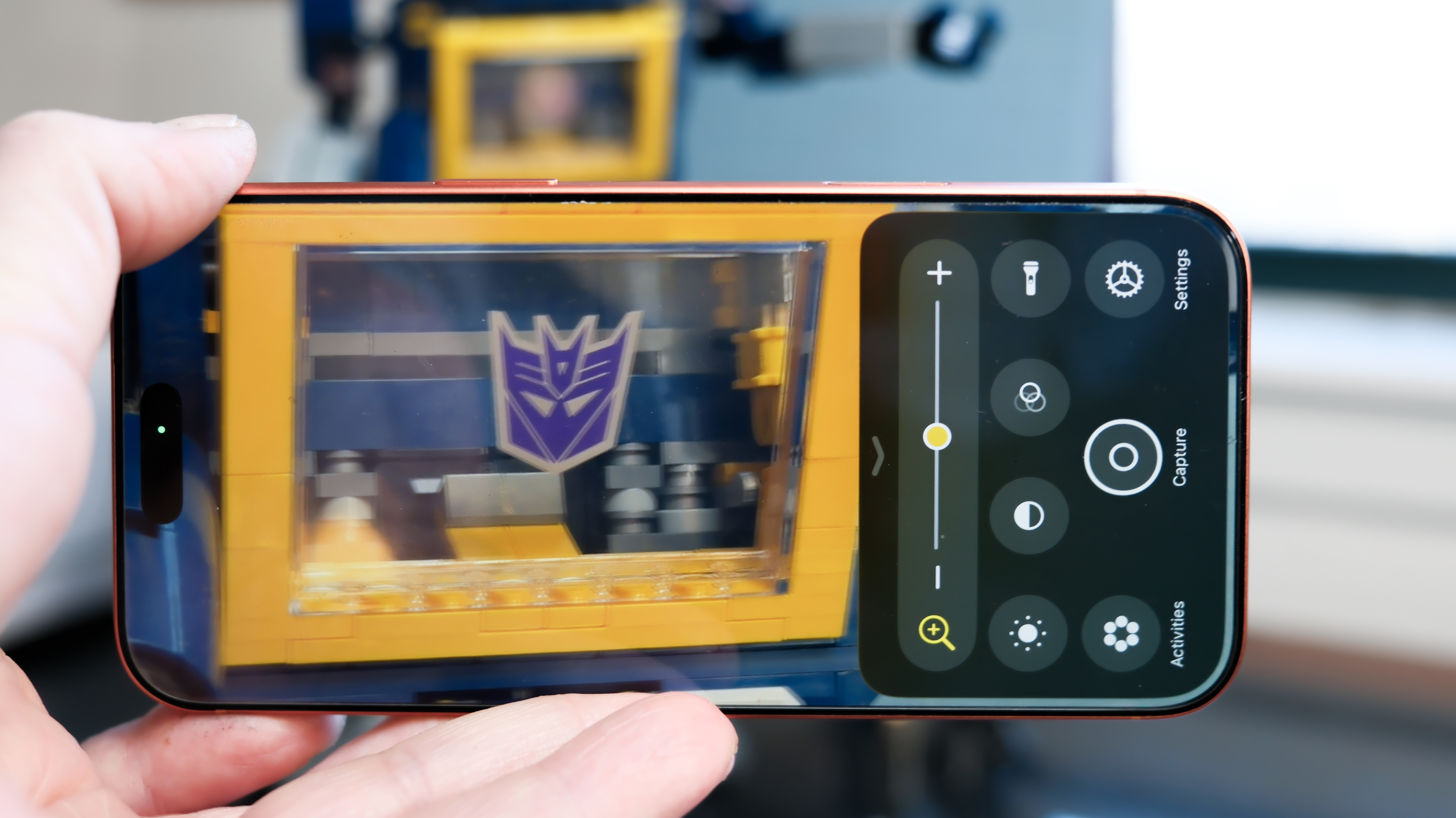 Camera Control button software features on the Apple iPhone 17 Pro Max in Cosmic Orange color, showing zoom, switching cameras, Magnifier app, and more
