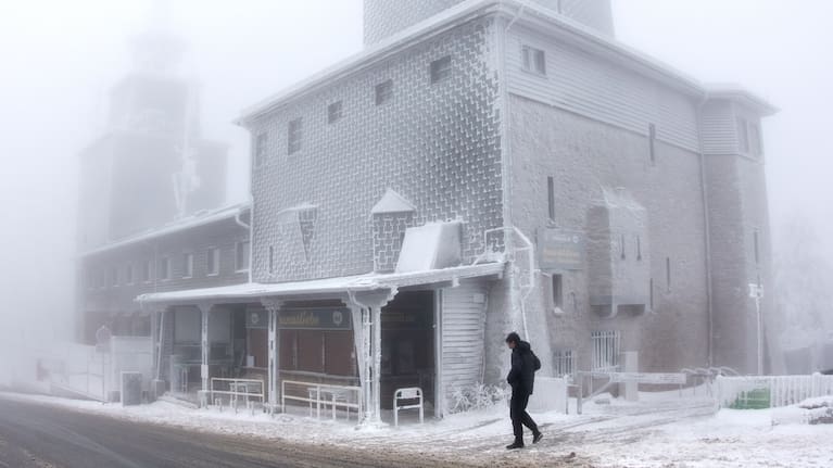 A man walks past an ice covered building on top of the Feldberg mountain near Frankfurt, Germany.