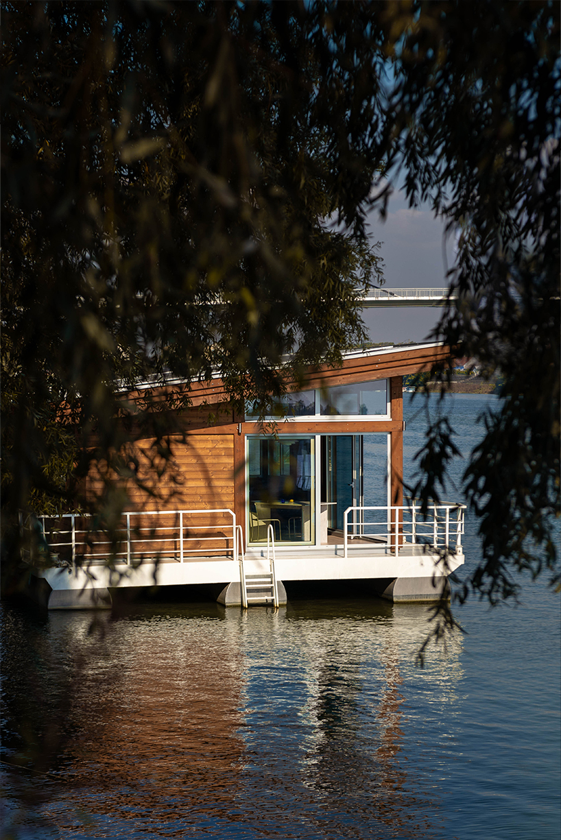 mono-pitch roof shields compact wooden cabin floating along river in serbia